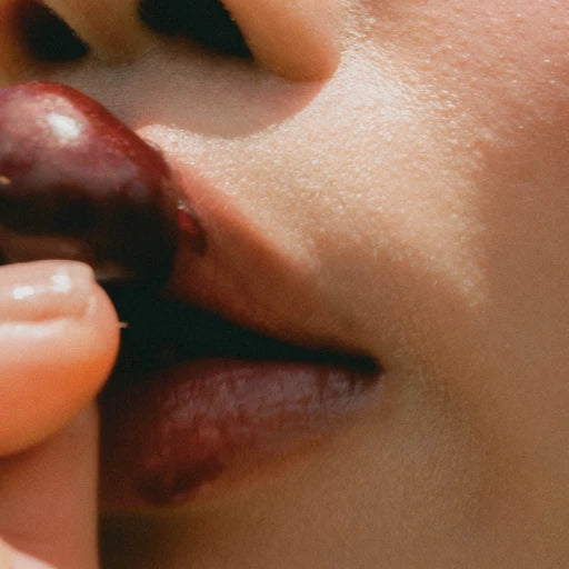 Language brand lifestyle image: cherry held near lips in natural light